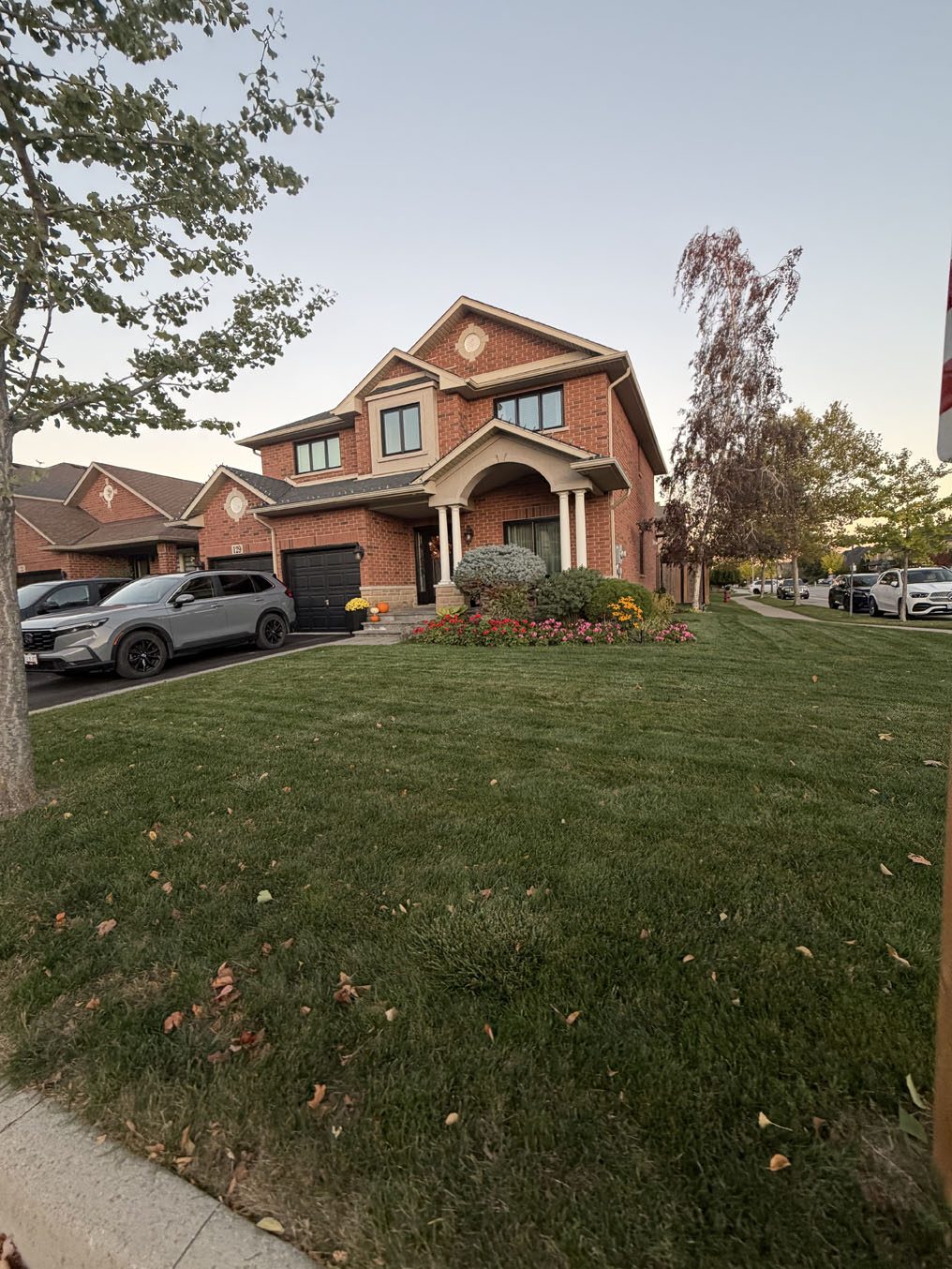 Wide corner-lot front lawn at a red-brick home with a columned porch in Hamilton