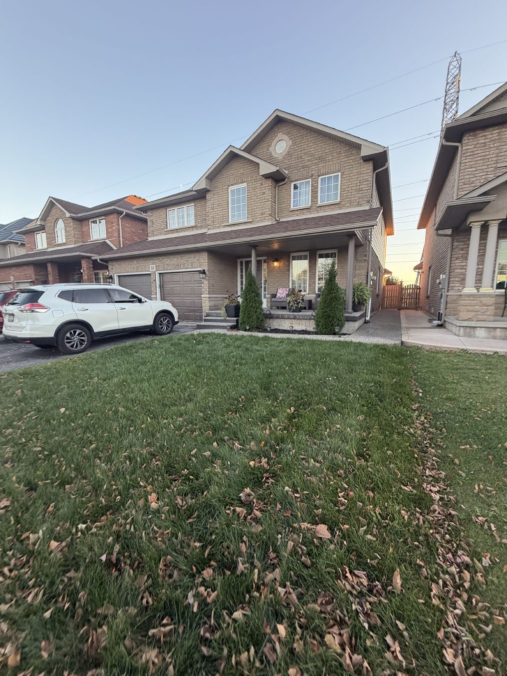 Established sod lawn with autumn leaves in front of a brick home in Hamilton