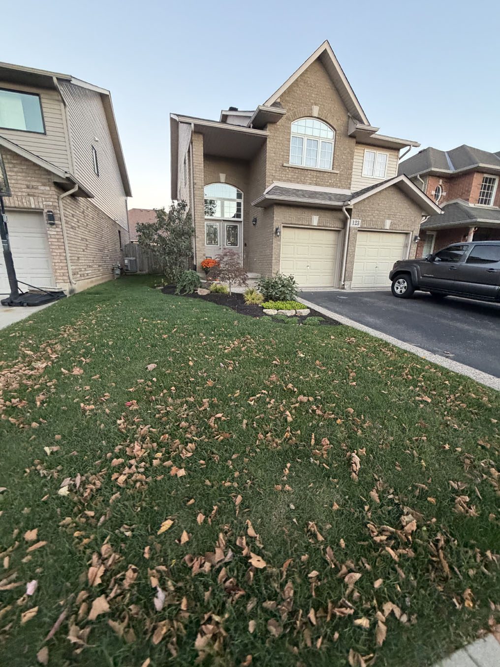 Front lawn with fall leaves in front of a double-garage home in Hamilton