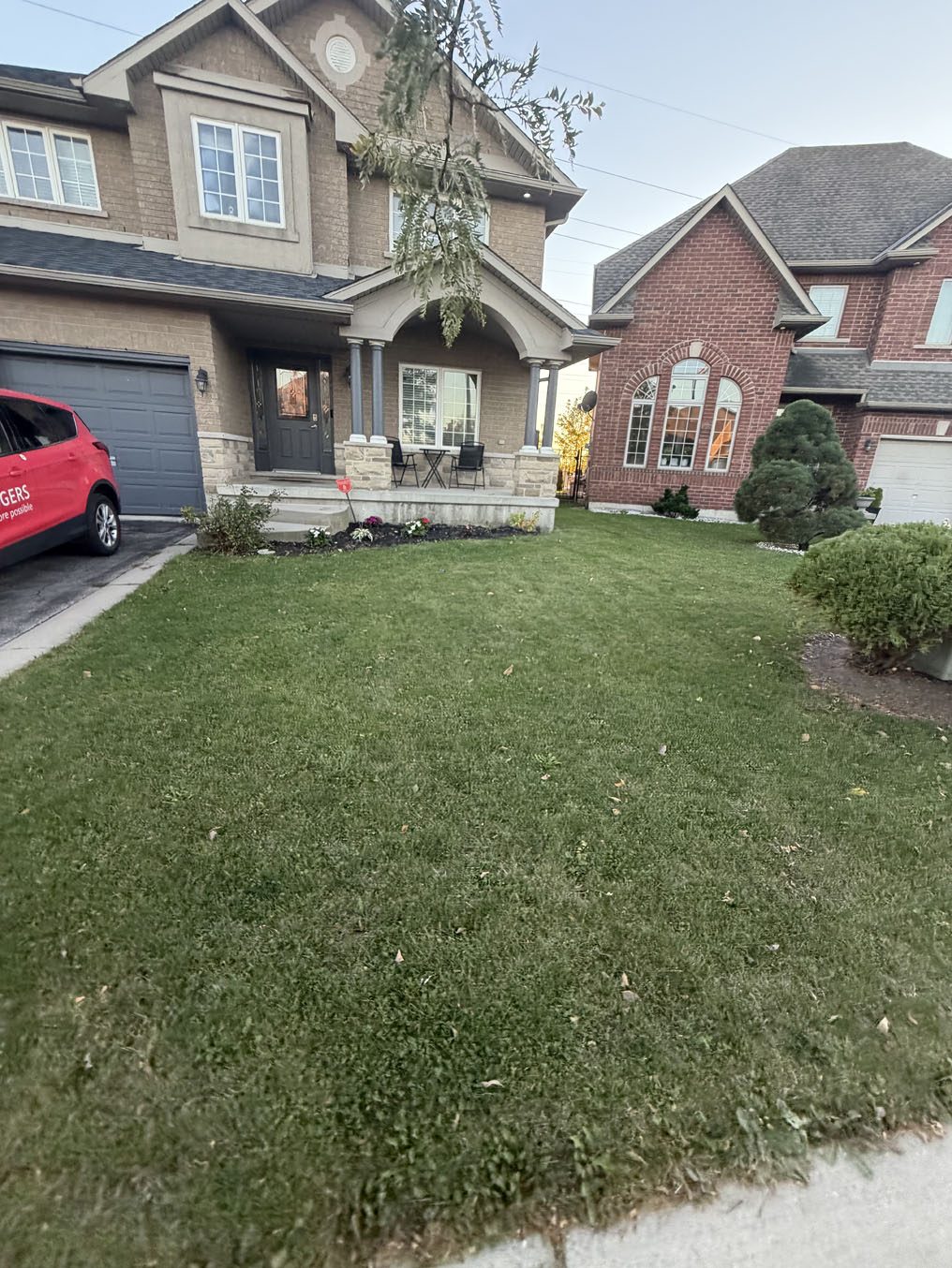 Healthy front lawn and rounded shrubs outside a stone and brick Hamilton home