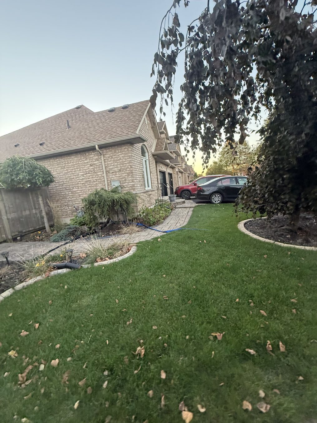 Side-yard sod lawn with a curved, stone-lined garden bed at a Hamilton home