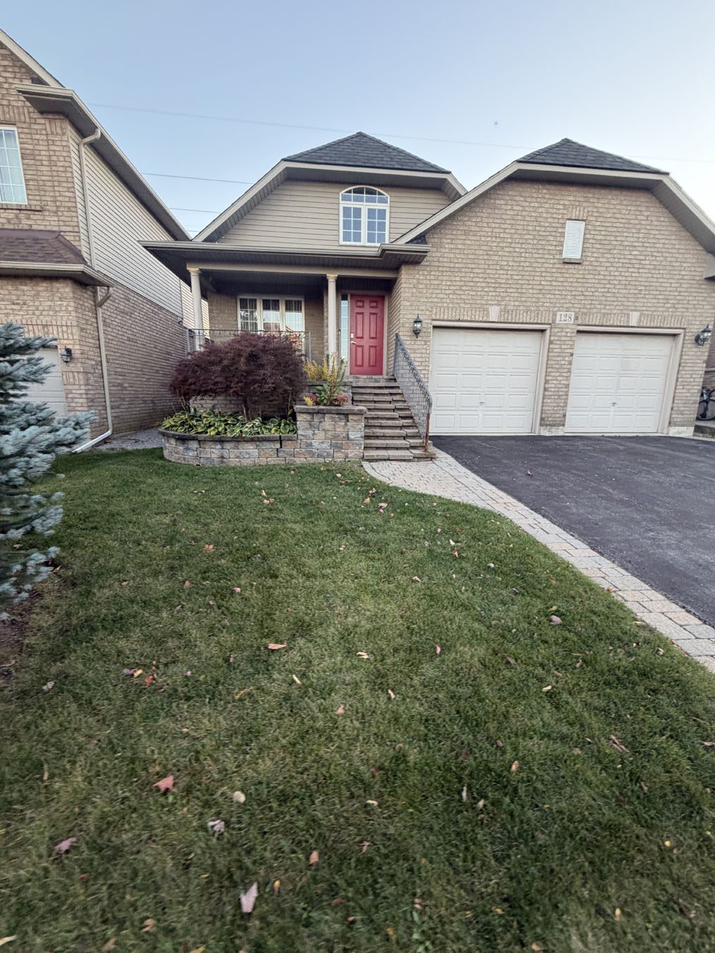 Sloped front lawn below a porch and red front door at a Hamilton home