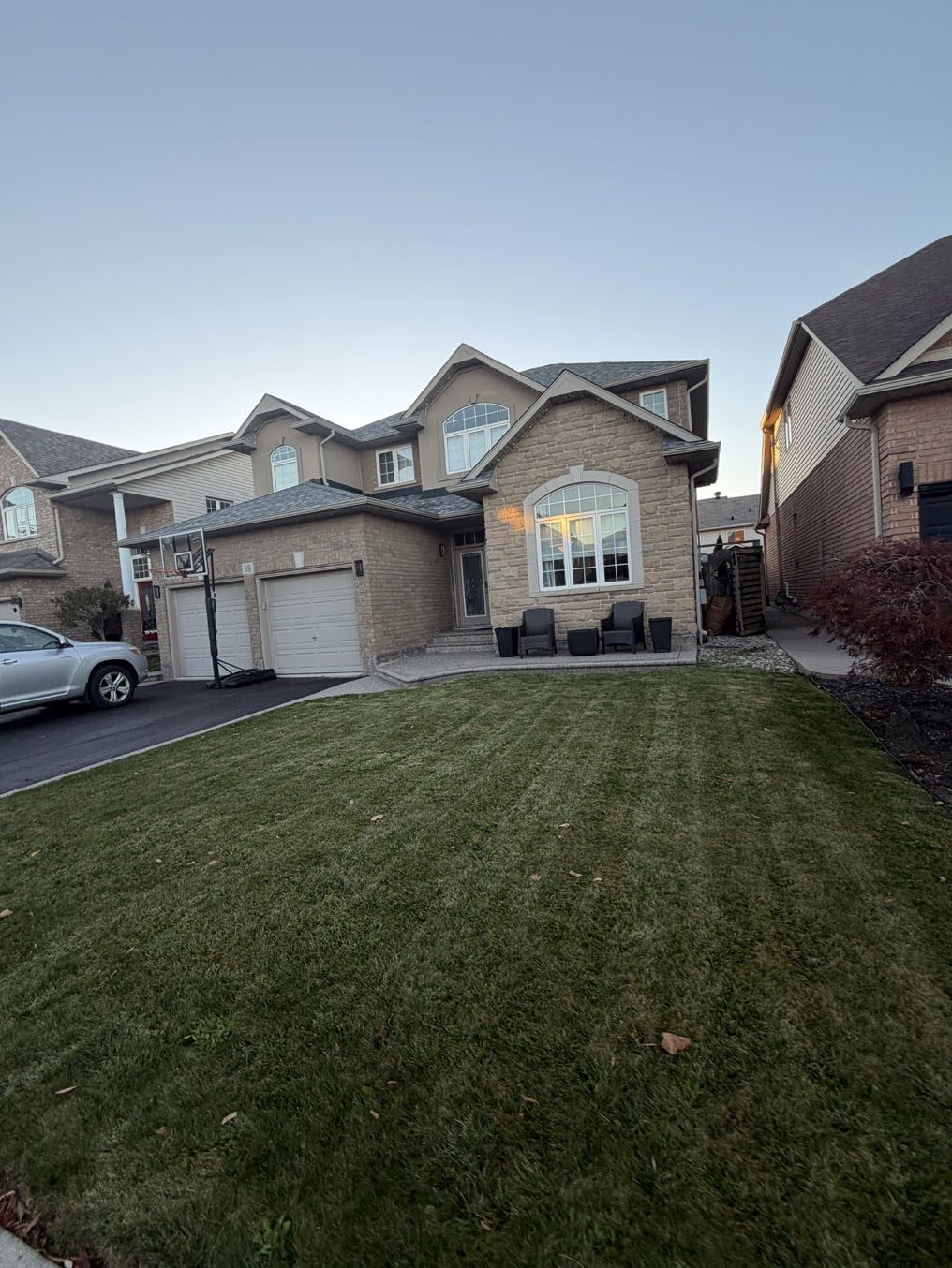 Freshly mowed, striped sod front lawn on a two-storey brick home in Hamilton by Right On Sod
