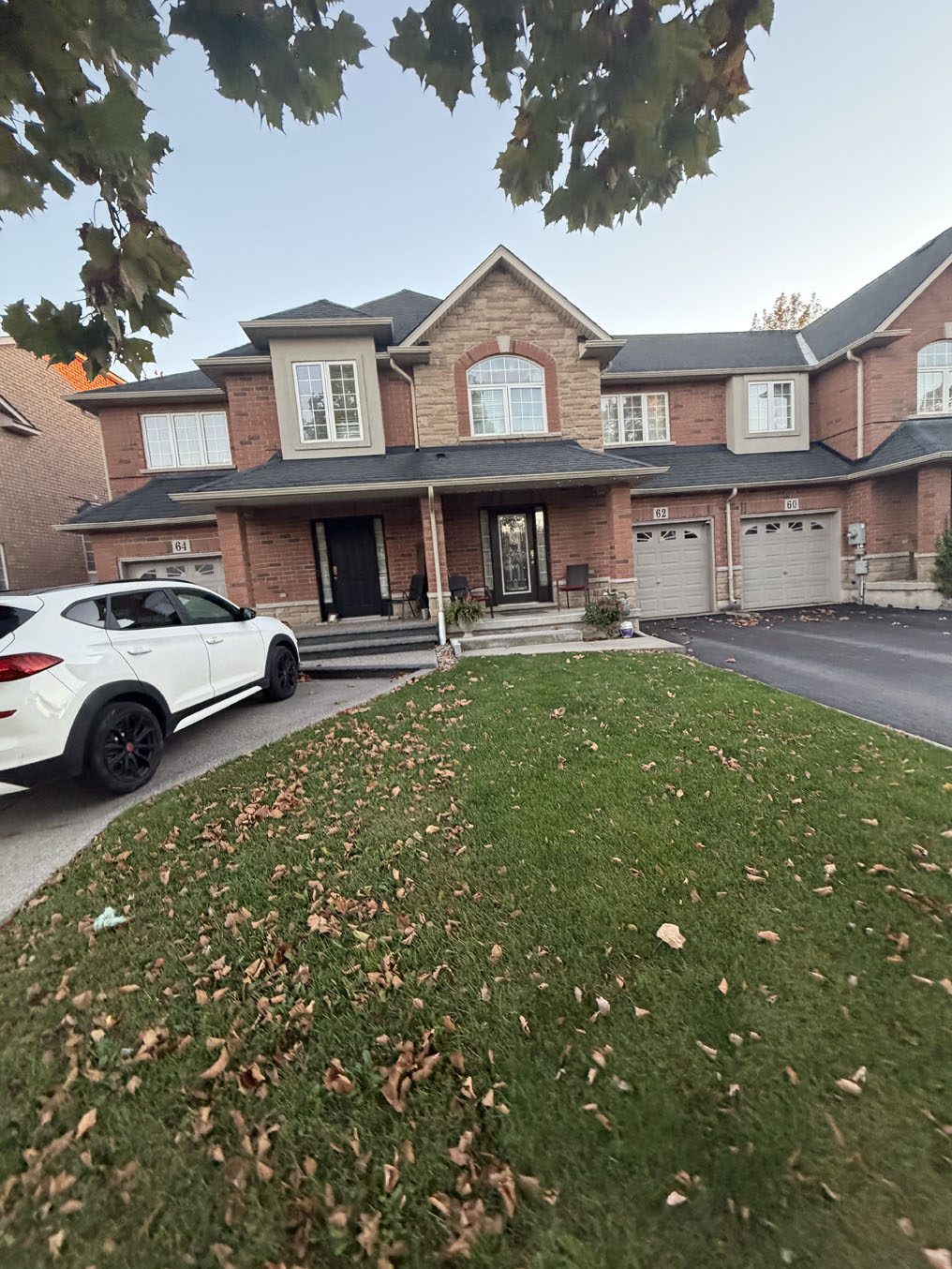 Townhome front lawn with scattered autumn leaves in a Hamilton neighbourhood